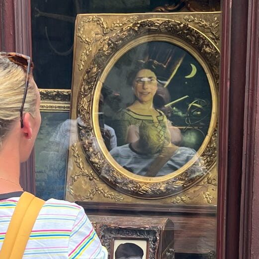 A person looking at a vintage-style mirror featuring a painted portrait of a woman in a historical setting.