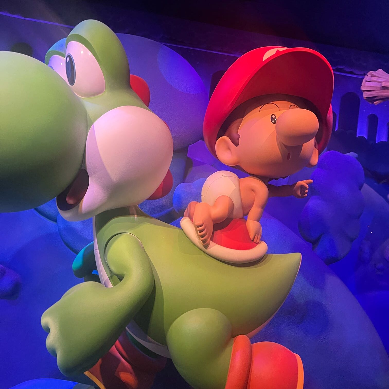 A colorful statue featuring Yoshi, a green dinosaur character from the Mario franchise, with a small character dressed in red riding on its back.
